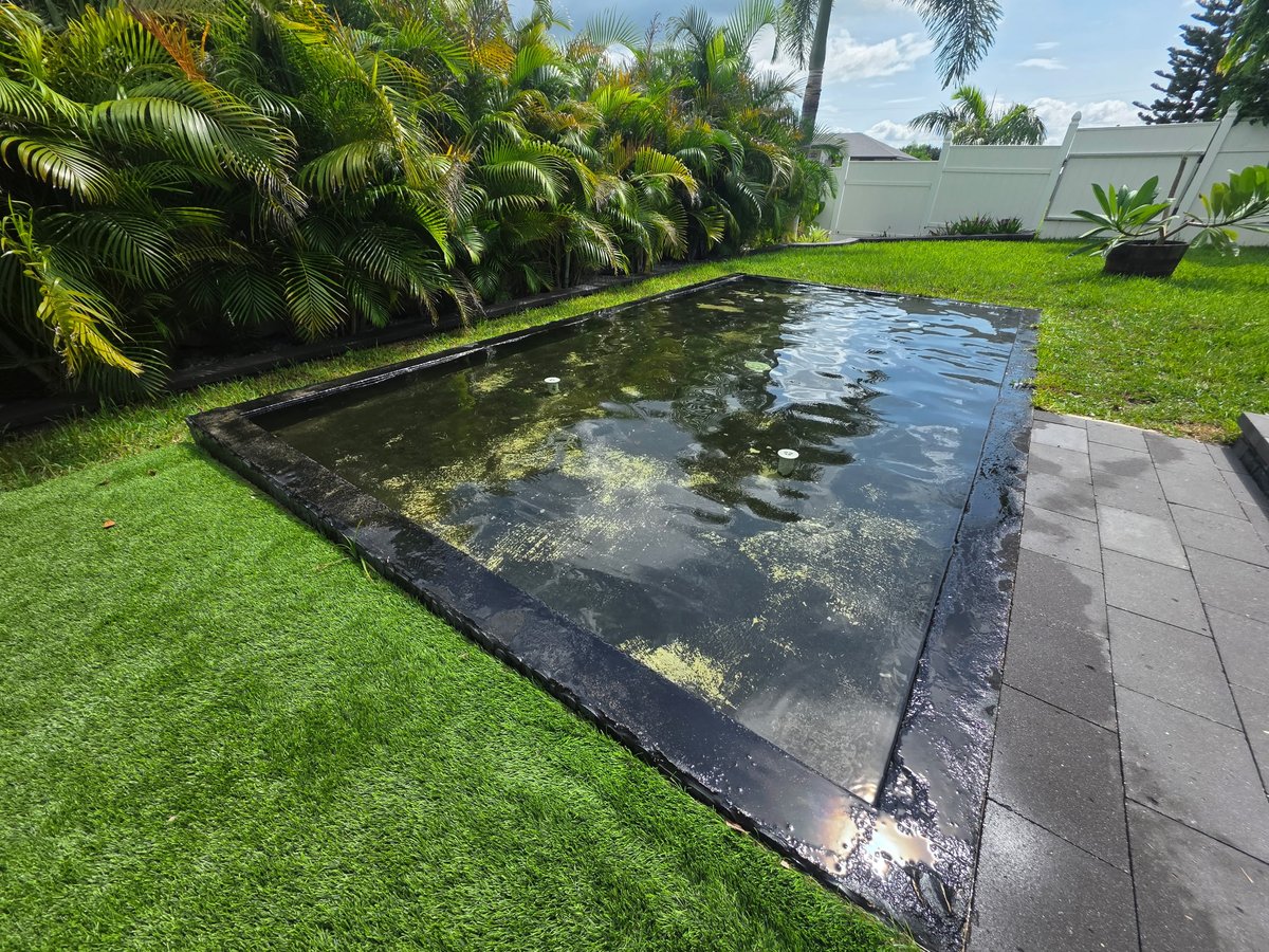 Client backyard water feature surrounded by tropical landscaping