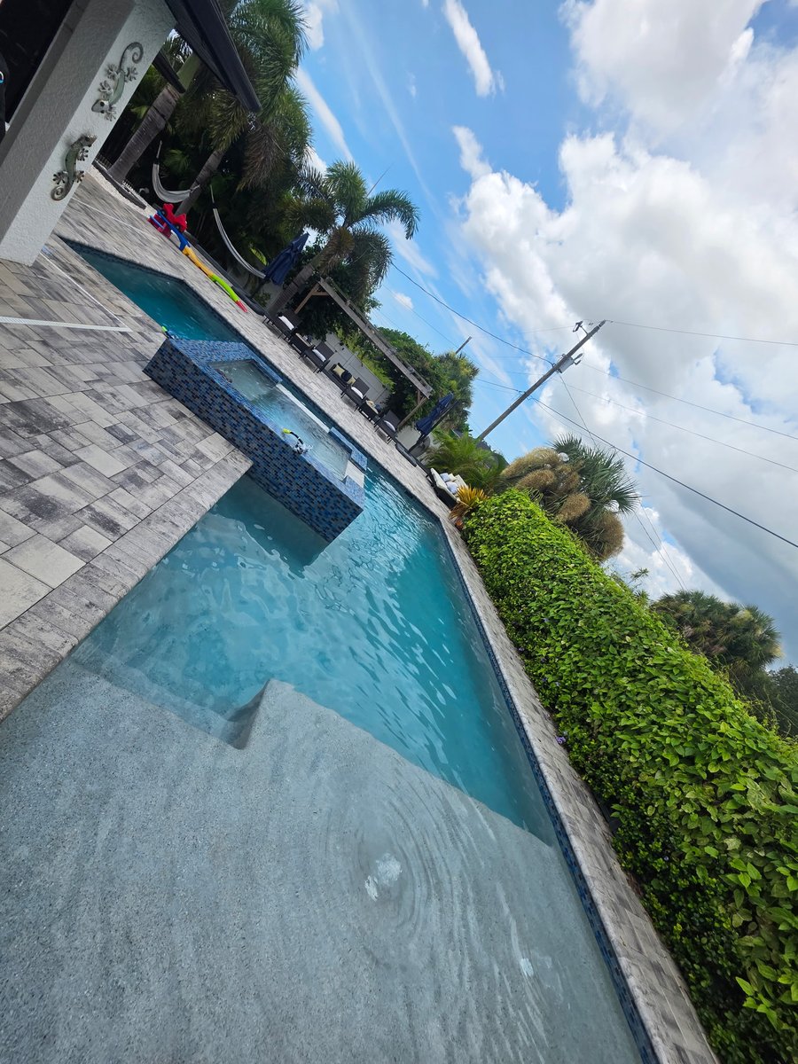 Sparkling modern client pool with spa and travertine deck